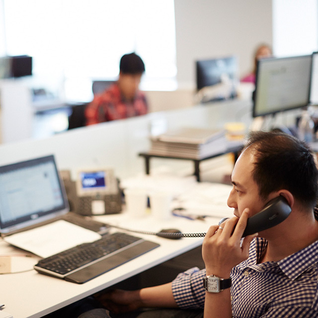 Man talking on the phone while sitting at his work space.