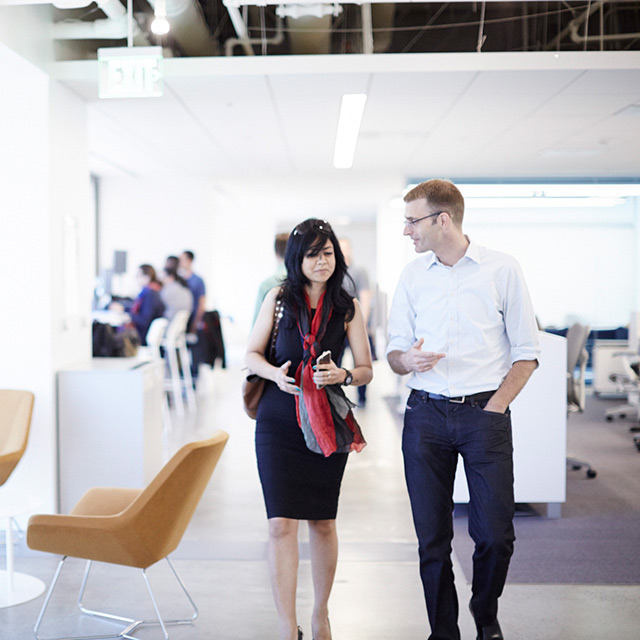Two people walking together in an office space.