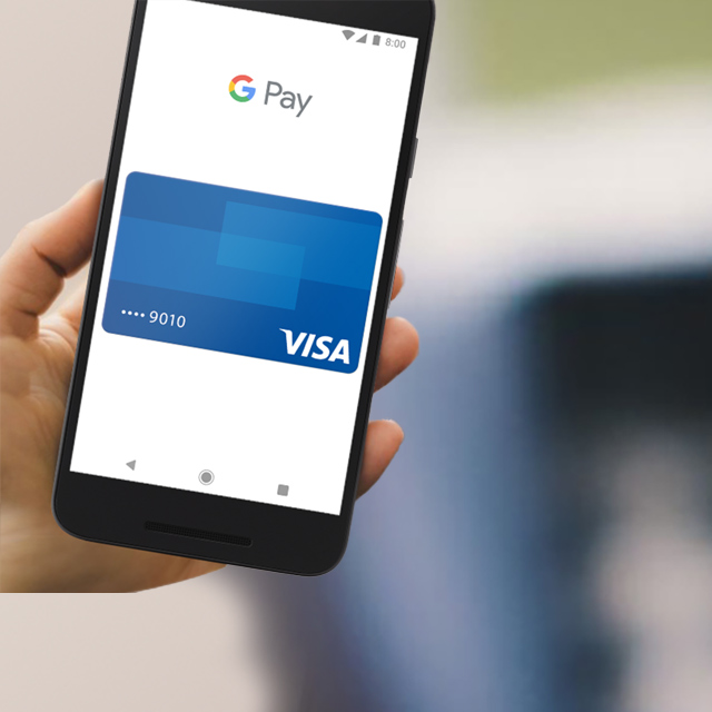 A hand holding a smartphone with a Visa PayWave card on the screen.